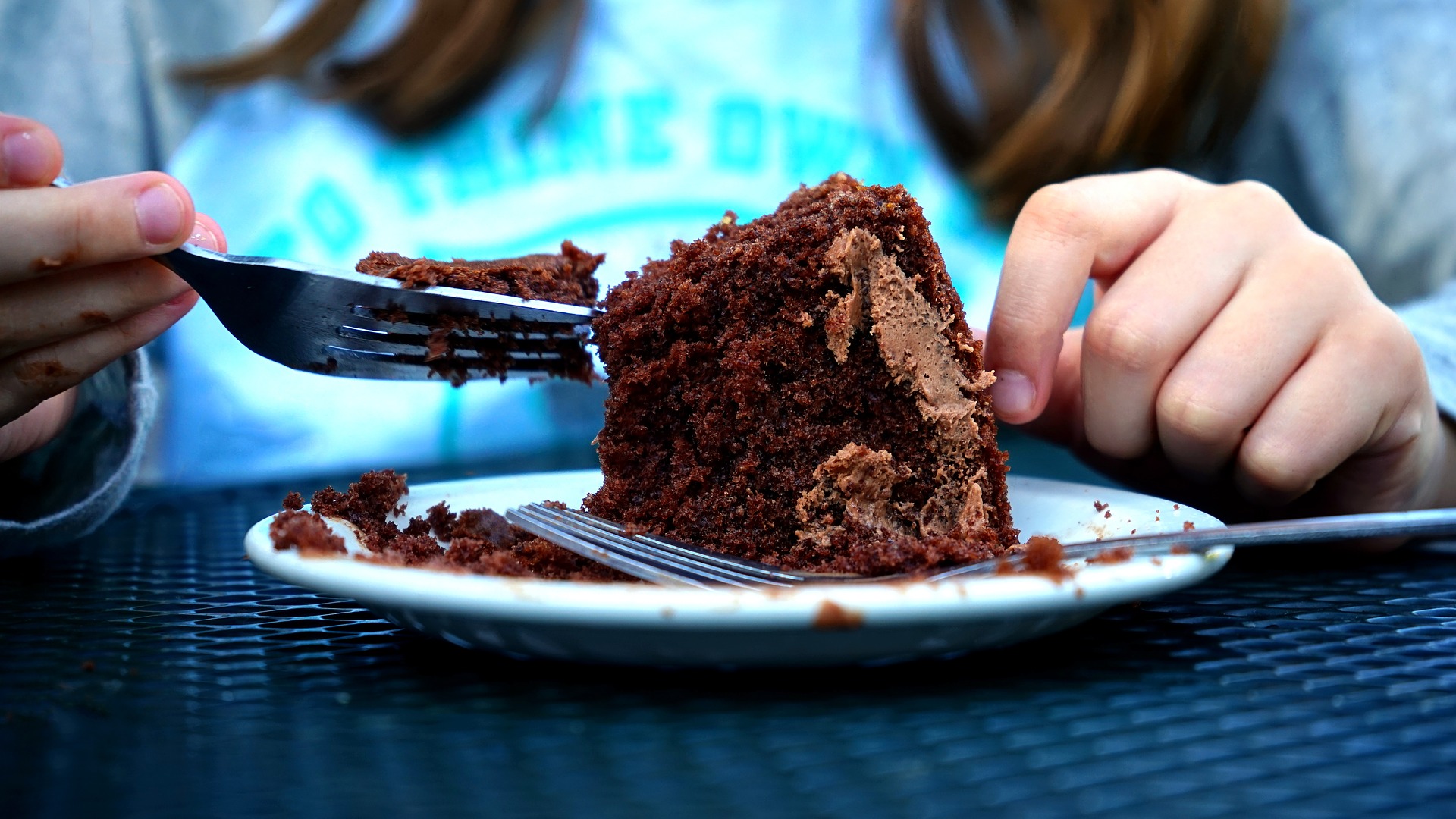 This image of a chocolate cake being devoured by someone with long brown hair and wearing a blue shirt is to invoke hunger for chocolate and the feeling of sadness